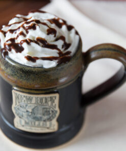 Photo of drink with whipped cream and 100部啪啪视频 syrup drizzle in a black pottery mug