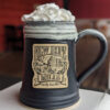 Photo of large 侮辱丰满美丽的人妻 logo pottery mug with whipped cream protruding from the top; black with white glaze
