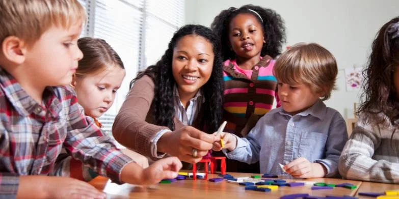 happy female teacher surrounded by children
