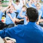 man sitting in front of class of children
