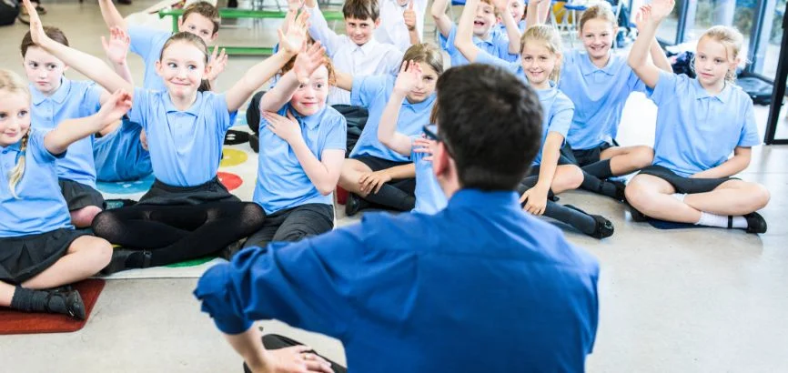 man sitting in front of class of children