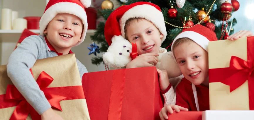 three young boys holding christmas presents