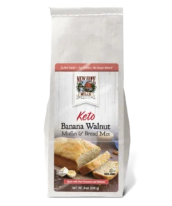 Front of the Keto Banana Walnut Muffin & Bread Mix, showing a loaf of bread with banana and walnut pieces on a jute canvas.